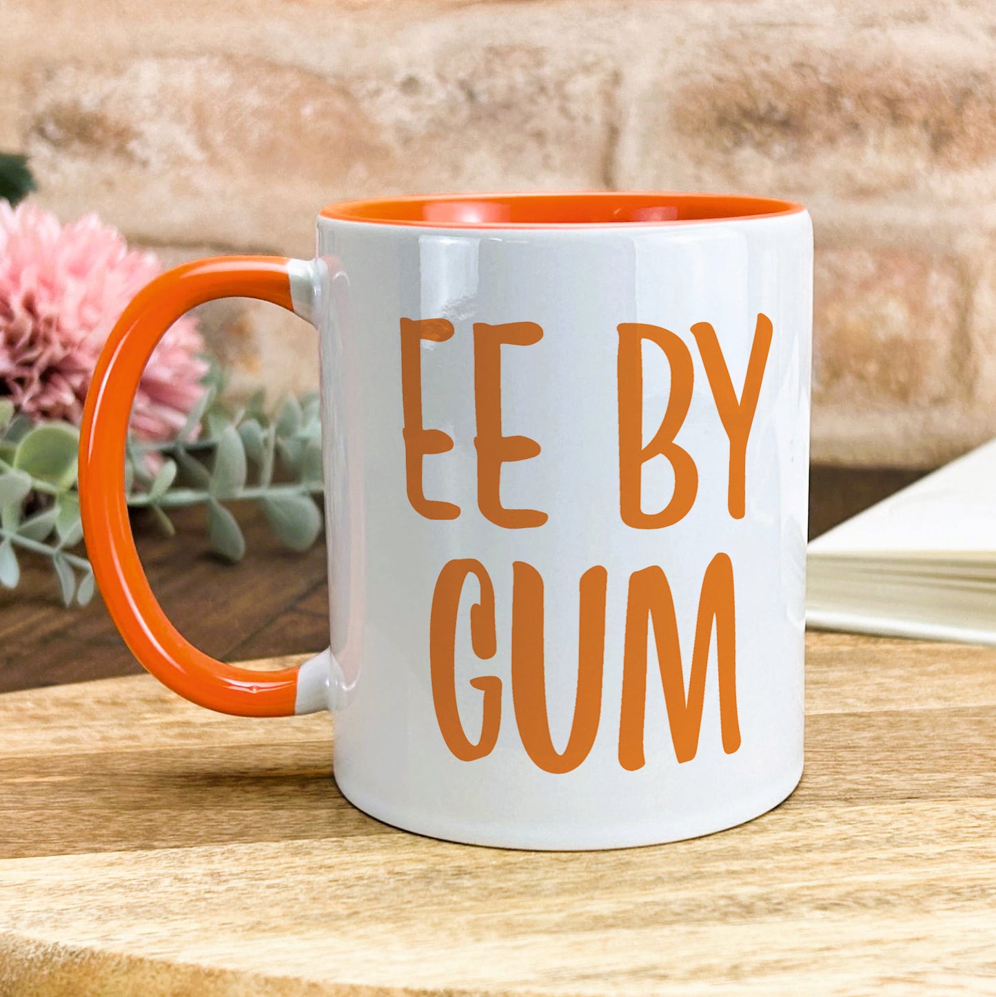 an orange and white coffee mug sitting on top of a wooden table