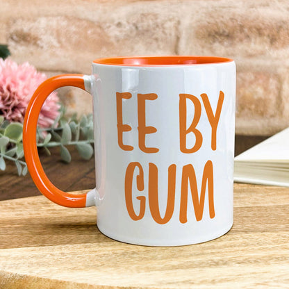 an orange and white coffee mug sitting on top of a wooden table