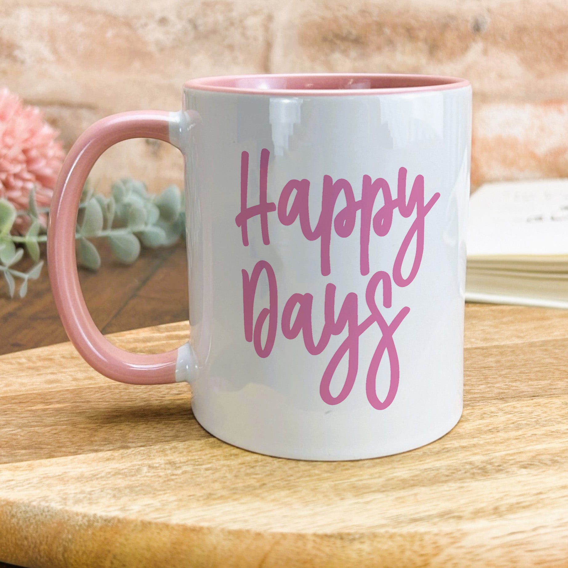 a pink and white coffee mug sitting on top of a wooden table