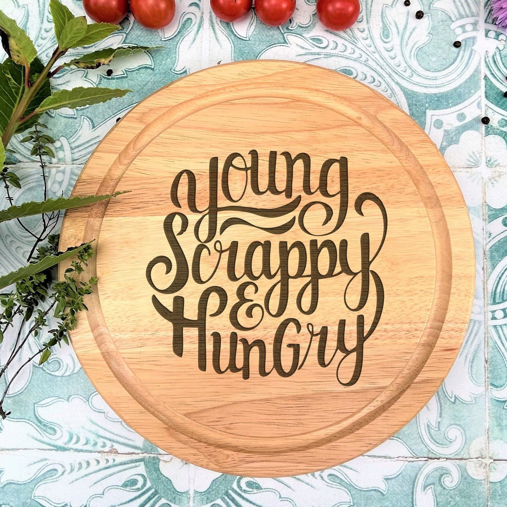 a wooden cutting board with the words young, happy, hungry on it