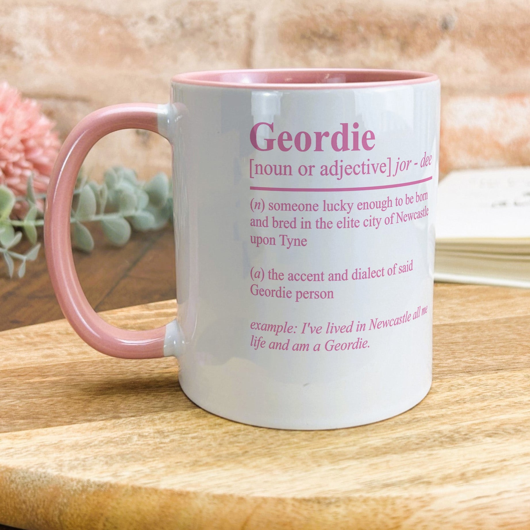 a pink and white mug sitting on top of a wooden table
