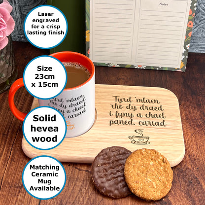 a wooden tray with a mug and two cookies on it, along with a note pad and a pen holder.