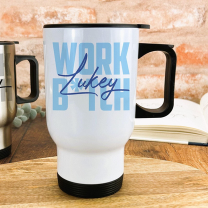 A white travel mug with the text "WORK LUCY" printed on it, sitting on a wooden surface.