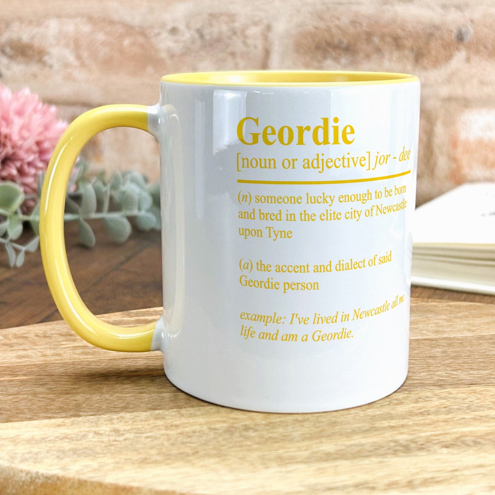 a yellow and white mug sitting on top of a wooden table