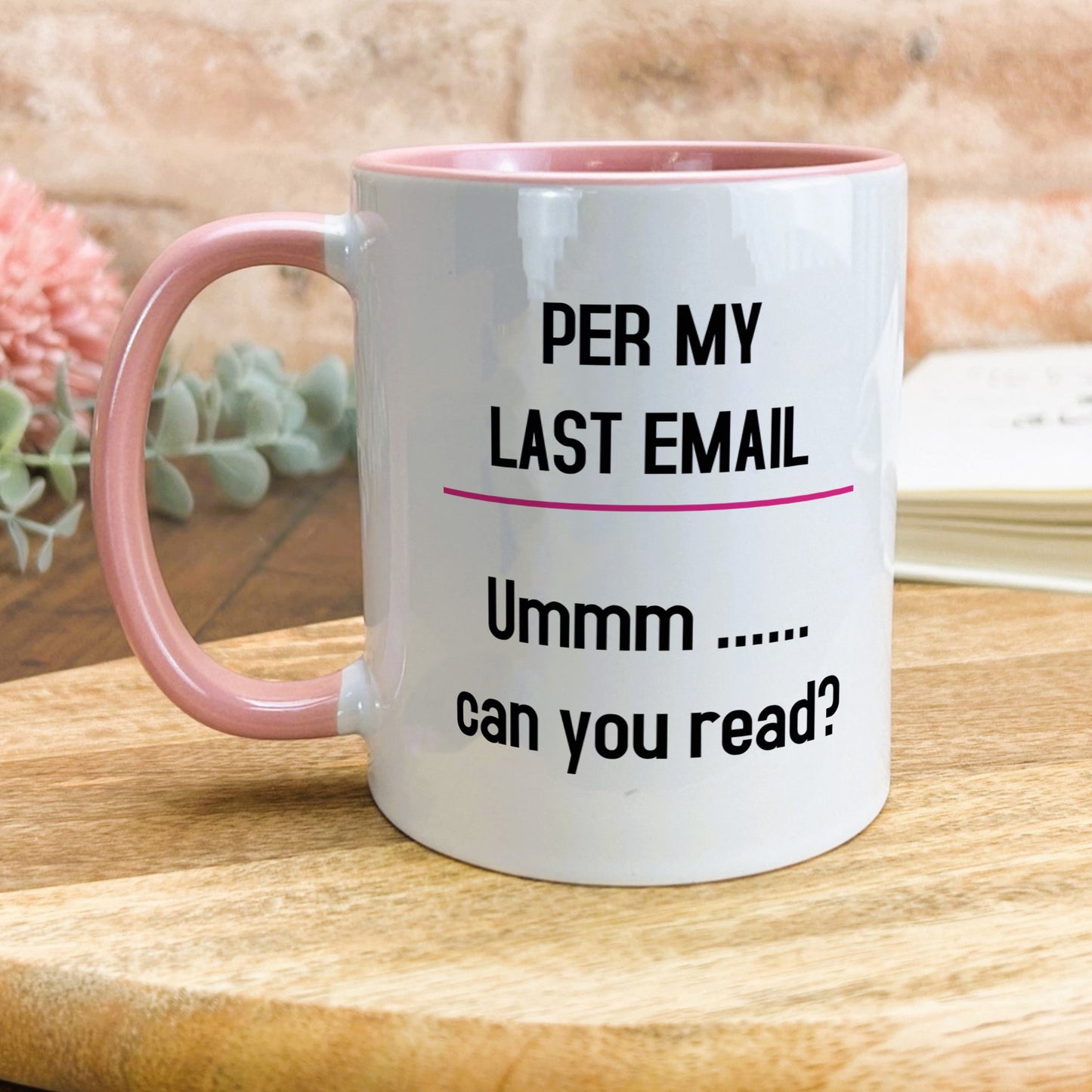 a pink and white coffee mug sitting on top of a wooden table
