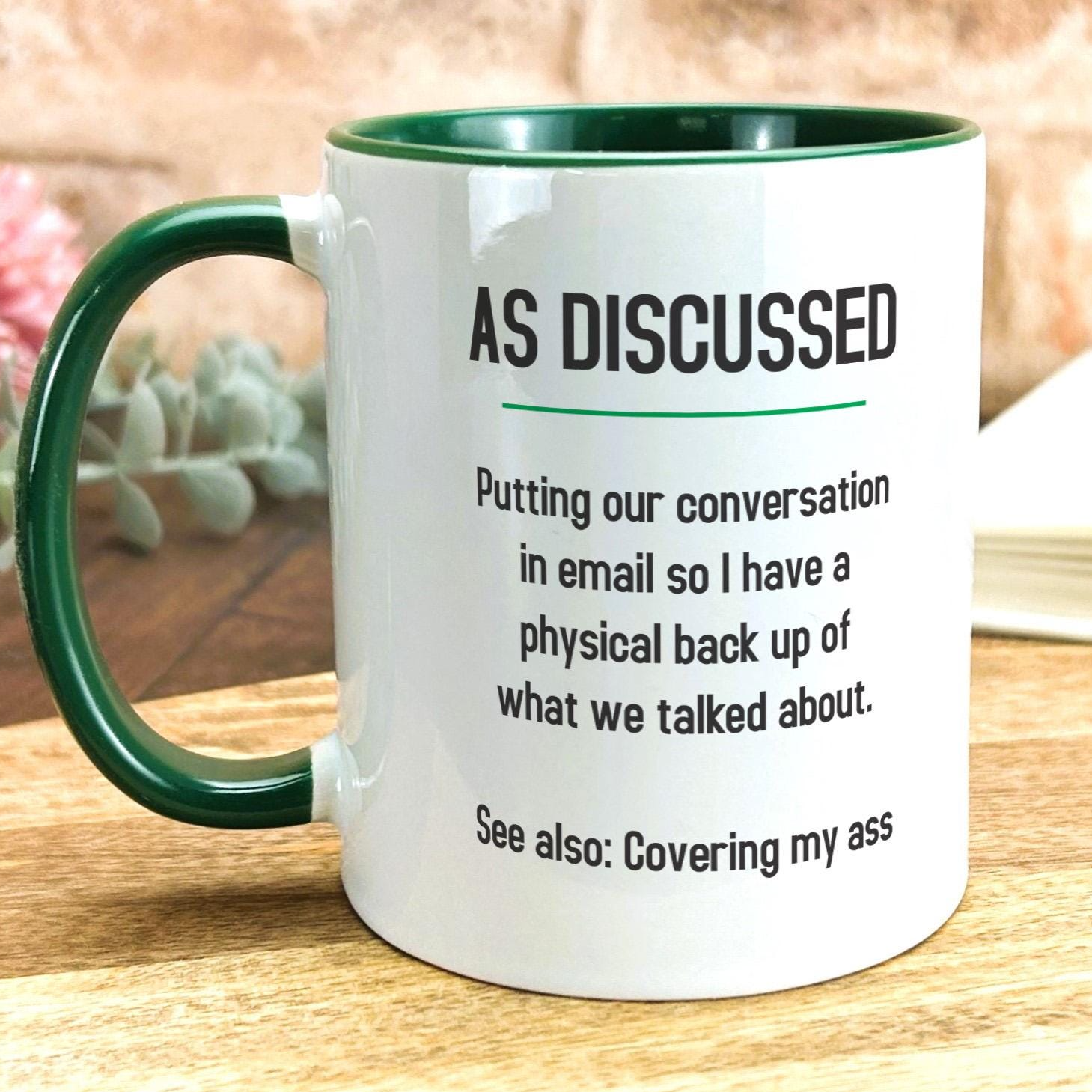 a green and white coffee mug sitting on top of a wooden table