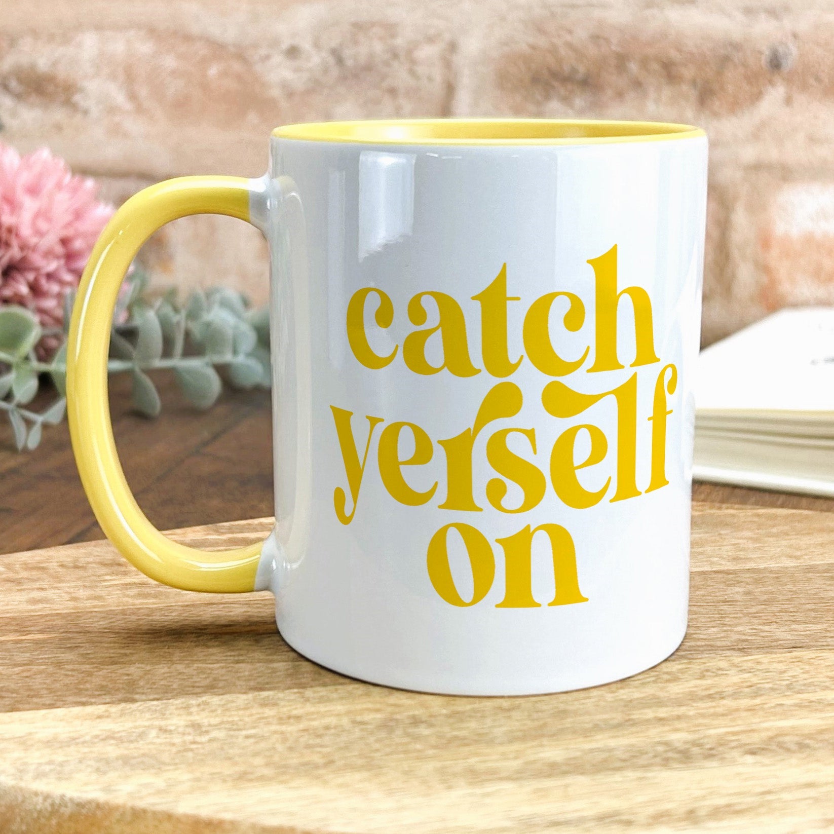 a yellow and white coffee mug sitting on top of a wooden table