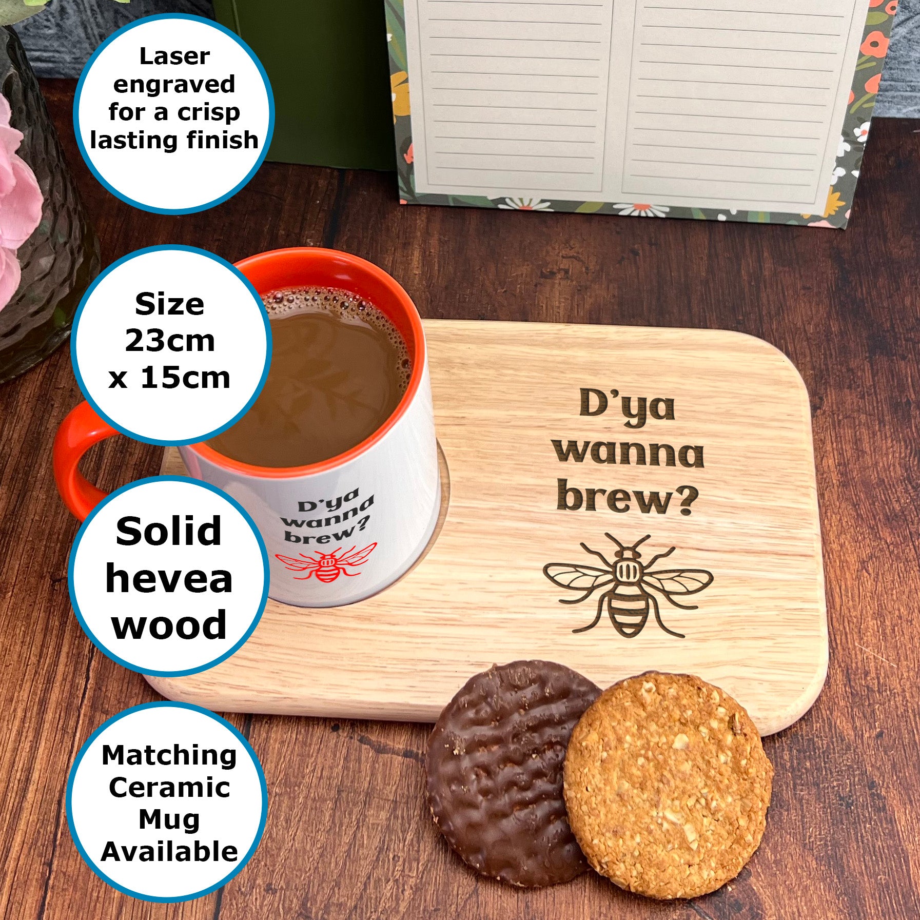 A wooden mug coaster with a printed design and a cup of coffee on it, along with a plate of cookies and a note.