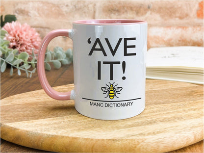 a pink and white coffee mug sitting on top of a wooden table