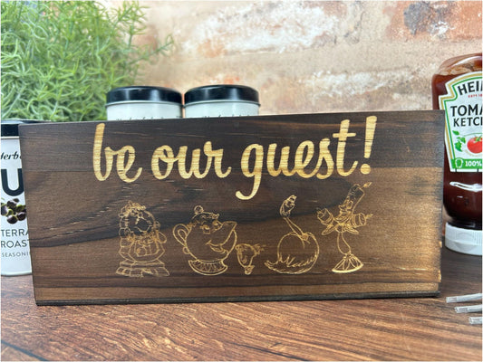 a wooden sign that says be our guest